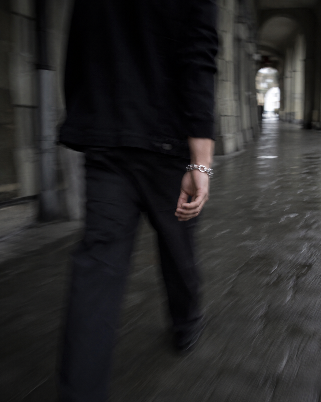 Walking through a Bern sandstone arcade wearing a steel chain bracelet